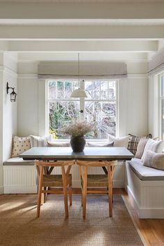 a dining room table and bench in front of a window with light coming through the windows