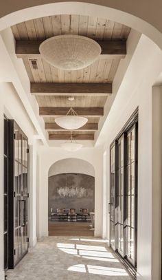 an archway leading to a dining room with large windows and wooden ceilinging, along with black doors