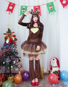 a woman dressed in a costume standing next to a christmas tree