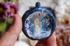 a hand holding a small blue ornament with crystals in it