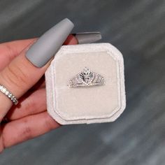 a person holding a ring in their hand with a diamond on the band and a white box