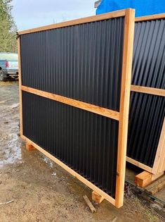 two large black and wood panels sitting next to each other on the side of a road