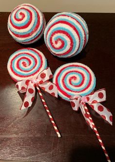 three lollipops are sitting on a table next to some candy canes