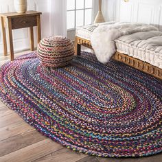 a multicolored braided rug is on the floor next to a wooden bed