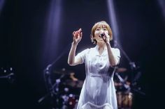 a woman in white dress singing on stage