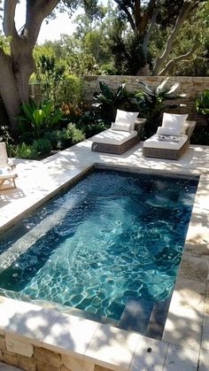 an outdoor swimming pool with lounge chairs and trees in the backgroung area