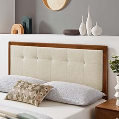 a bed with pillows and decorative items on the headboard, along with vases