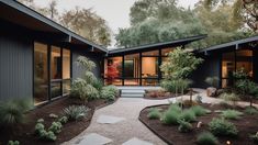 a modern house with lots of windows and plants in the front garden area, along with gravel pathway leading up to it