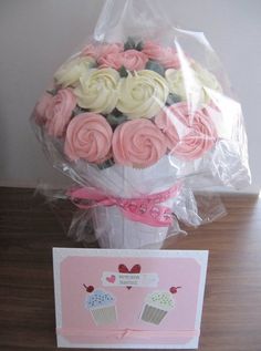 a bouquet of pink and white cupcakes next to a card