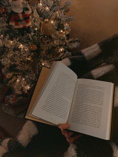 an open book sitting in front of a christmas tree