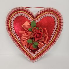 a red heart shaped box with a rose on it