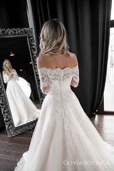 a woman in a white wedding dress looking at herself in the mirror with her reflection