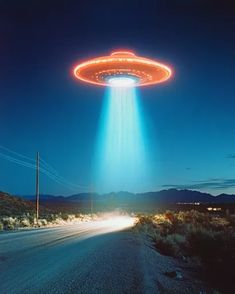 an alien flying over a road in the middle of the night with light beams coming from it