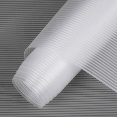 a close up of a white pleated material on a gray background with vertical lines