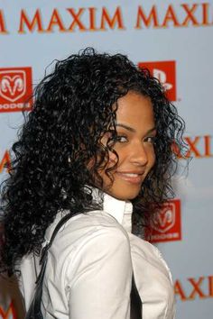 a woman with long curly hair wearing a white shirt and black tie