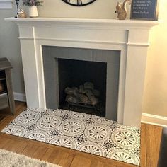 a fireplace with a clock above it and rugs on the floor next to it