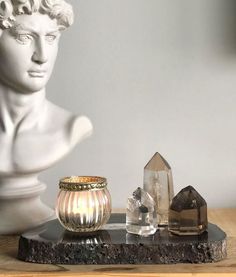 a white busturine sitting on top of a wooden table next to crystal stones