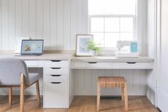 a white desk with two chairs and a laptop on it in front of a window