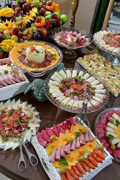 a table topped with lots of trays of food next to fruit and dessert dishes