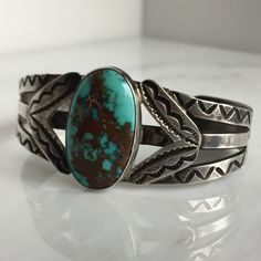 "Details: Lovely Native American Sand Cast Turquoise and Silver Bracelet. The turquoise is a deep blue with silver veins, and measures 1\" x 3/4\", and the face of the bracelet measures 1 3/4\" high. This piece has a nice weight to it. Please ask all necessary questions prior to placing an order. Measurements: The bracelet is a cuff, and can be adjusted to fit small to medium wrists. The interior measures 2 1/2 across, and the interior measures 5 1/2 inches.. Condition: The overall all condition Turquoise Cuff Bracelet With Polished Finish, Unique Blue Oval Cuff Bracelet, Southwestern Blue Cuff Bracelet With Patina, Southwestern Blue Patina Cuff Bracelet, Southwestern Engraved Blue Cuff Bracelet, Classic Turquoise Cuff Bracelet Gift, Adjustable Turquoise Cuff Bracelet With Polished Finish, Adjustable Turquoise Polished Cuff Bracelet, Artisan Blue Engraved Cuff Bracelet