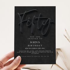 a hand holding up a black birthday card with the word festy on it in cursive font