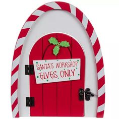 a santa's workshop door with candy canes and holly on the front sign