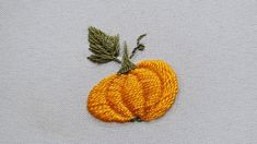 an embroidered pumpkin sitting on top of a white cloth