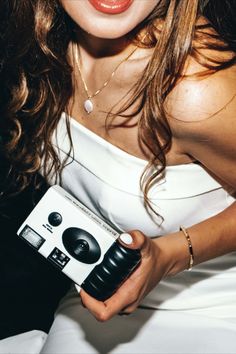 a woman in a white dress is holding a black and white box with an earphone on it