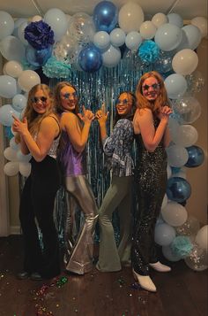 three women pose for a photo in front of balloons and streamers