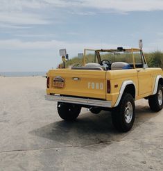 a yellow truck parked on top of a sandy beach