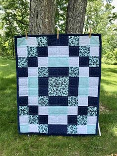 a blue and white quilt hanging from a tree