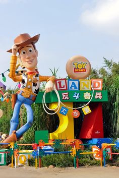 a toy story land sign with woody the cowboy on it's head and toys in front