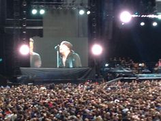 a large crowd is watching two men on stage in front of an audience at a concert