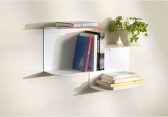 a white shelf with books and plants on it