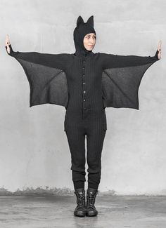 a woman wearing a bat costume standing in front of a wall with her arms outstretched