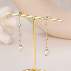 Elevate your look with our 14K Gold Plated Pearl Chain Dangle Earrings. Featuring three stunning cubic zirconia stones and two 6mm fresh pearls, these earrings are available in gold and silver. Perfect for everyday wear or as a special gift for someone you love. Materials: 925 sterling silver Features: 48mm height, 3mm cubic zirconia stone, 6mm fresh pearl