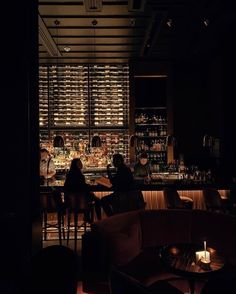 two people sitting at a bar in the dark with their backs turned to the camera