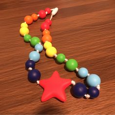 a wooden bead necklace with a red star on it and multicolored beads