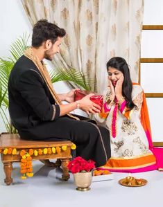 a man kneeling down next to a woman holding a red gift in front of her