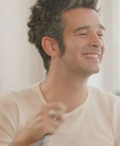 a man is smiling as he straightens his hair in front of a window with an electric toothbrush