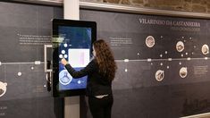 a woman standing in front of a display with information on the wall and an interactive screen