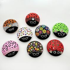 six painted ladybug buttons sitting on top of a white table next to each other