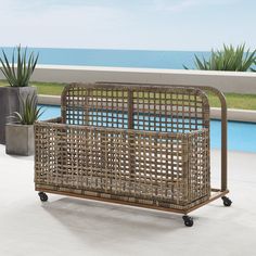 a wicker bed frame with wheels on the patio next to a pool and ocean