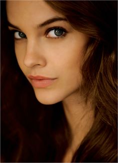 a beautiful young woman with blue eyes and long brown hair looking at the camera while posing for a photo