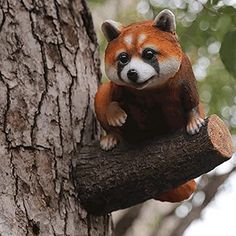 a small red panda bear sitting on top of a tree branch next to a tree