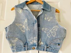 Beautiful light washed denim zipper vest. This is a DIY design made from a pair of Upcycled Wrangler jeans. #denimvest #recycleddenim #upcycleddenim #recycledfashion #butterflies #Stenciledenim #Denimclothes #denimstyle #denimfashion Summer Festival Medium Wash Denim Vest, Casual Upcycled Denim Vest For Spring, Summer Acid Wash Denim Jacket, Spring Acid Wash Denim Vest, Casual Upcycled Sleeveless Denim Vest, Trendy Patchwork Denim Vest, Fitted Cotton Patchwork Denim Vest, Beachy Accessories, Vintage Denim Vest With Button Closure