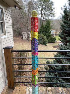 a multicolored pole sitting on top of a wooden deck next to a house