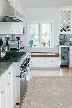 a kitchen with white cabinets and an area rug in front of the stove top oven