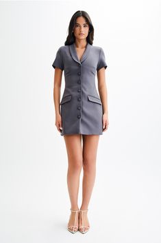 Suit-ableThe PAOLINA Collared Suiting Mini Dress is a chic and sophisticated addition to your wardrobe. Featuring a V neckline with a collar and lapel, it exudes timeless elegance with a hint of modern flair. The functional center front button closure adds a touch of polish, while the non-functional front pockets offer a stylish detail. With short sleeves, it's perfect for warm-weather wear, and the mini length adds a flirty touch to the ensemble. Whether dressed up with heels for a formal occas Chic V-neck Single Breasted Mini Dress, Classic V-neck Blazer Dress For Semi-formal, Classic V-neck Mini Dress For Semi-formal Occasions, Classic Fitted V-neck Blazer Dress, Business V-neck Dresses With Button Closure, Single Breasted V-neck Evening Dress, Sleek Blazer Dress With Lapel Collar For Semi-formal Occasions, Sleek Blazer Dress With Lapel Collar For Semi-formal Events, Sleek Semi-formal Blazer Dress With Lapel Collar