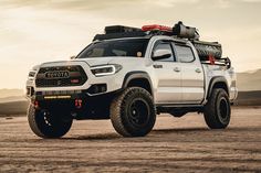 a white toyota truck parked on top of a dirt field